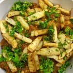 Kashmiri chicken served in a white bowl with fried potatoes.