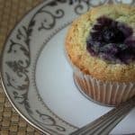 Blueberry muffin in a white saucer.
