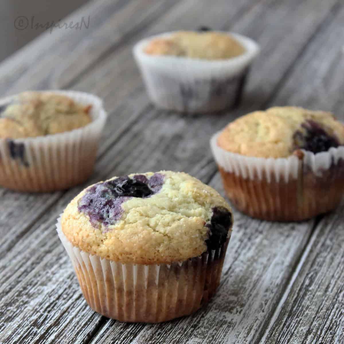 Bakery style blueberry muffins on a wooden plank.