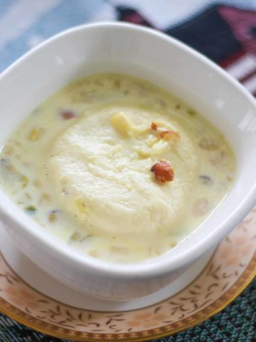 Rasmalai topped with nuts served in a white bowl.