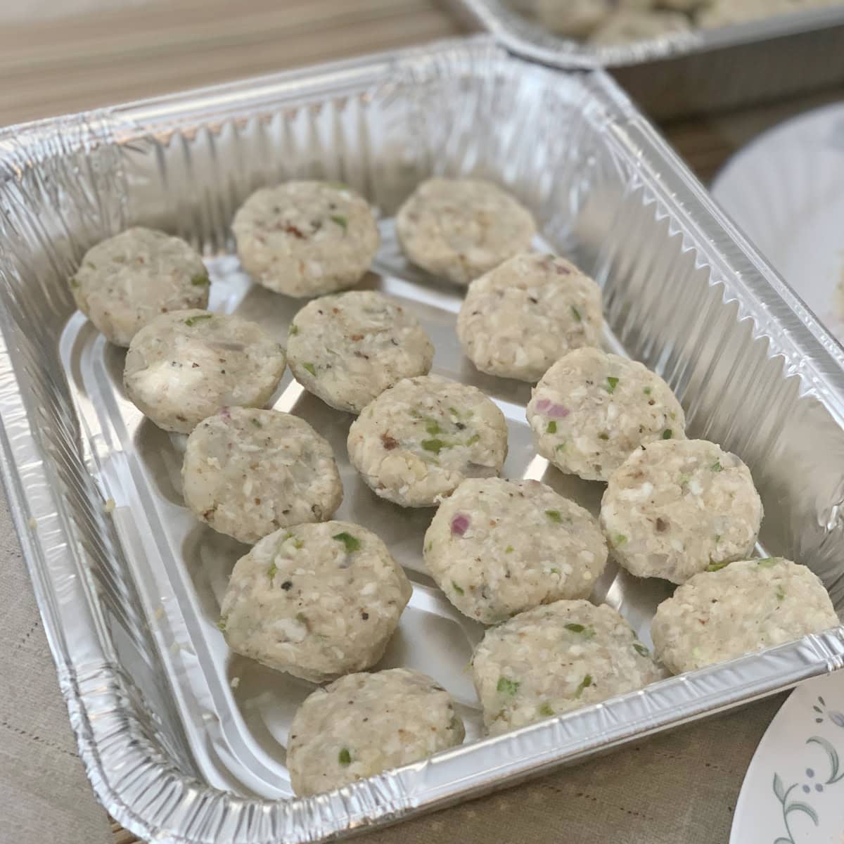 Fish cutlet patties in an aluminum tray.