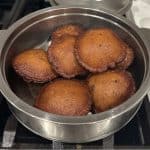 Neyyapams deep-fried and in a steel container.