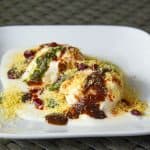 Soft Dahi Vada Recipe used to make vadas dunked in yogurt sauce , chutney and crispy fritters served in a white plate.
