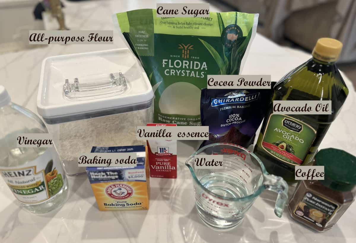 Eggless chocolate cake ingredients needed labelled and displayed on a white counter.
