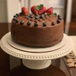 A chocolate cake made with chocolate cake ganache recipe with berries on top.