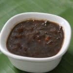 Inchipuli served in a white bowl placed on a green banana leaf.