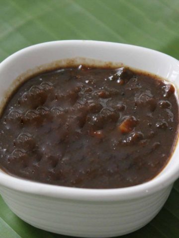 Inchipuli served in a white bowl placed on a green banana leaf.