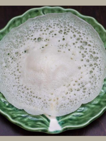 A green plate topped with a Vellappam .