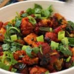 A bowl of food with chicken 65 made with chicken 65 dry recipe and garnishes.