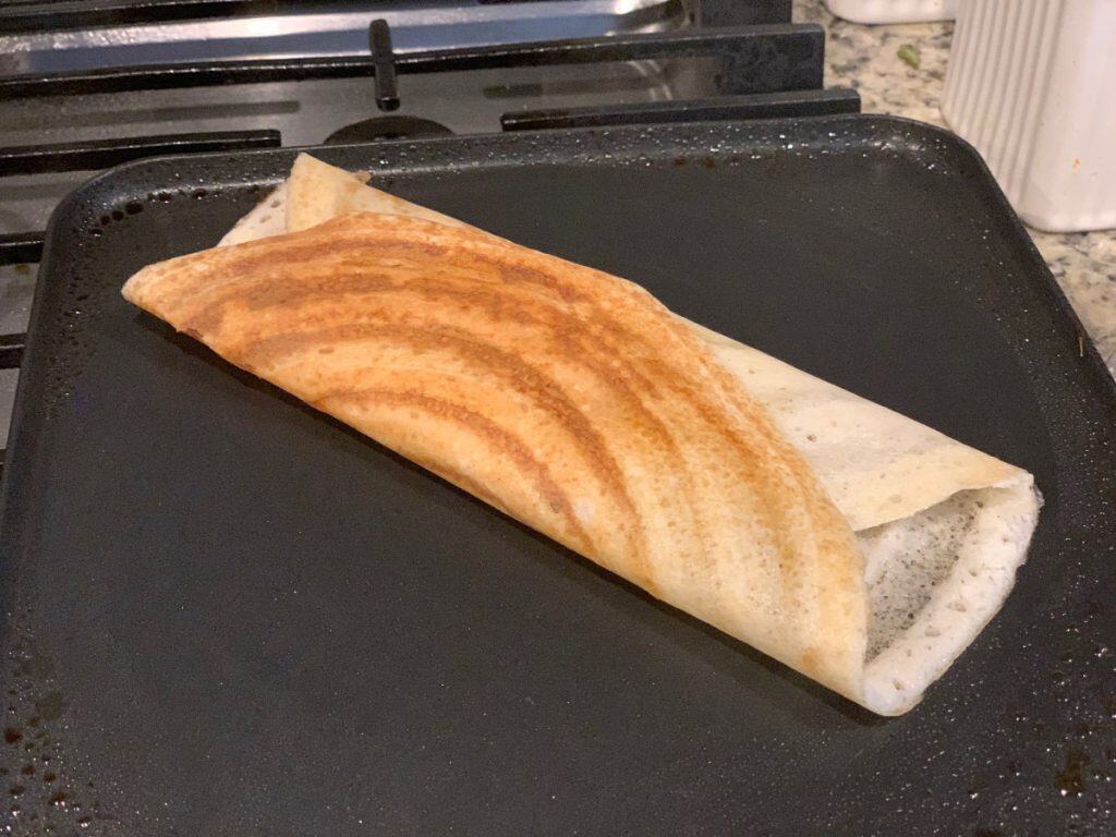 Aloo masala dosa on a pan on a stove top.