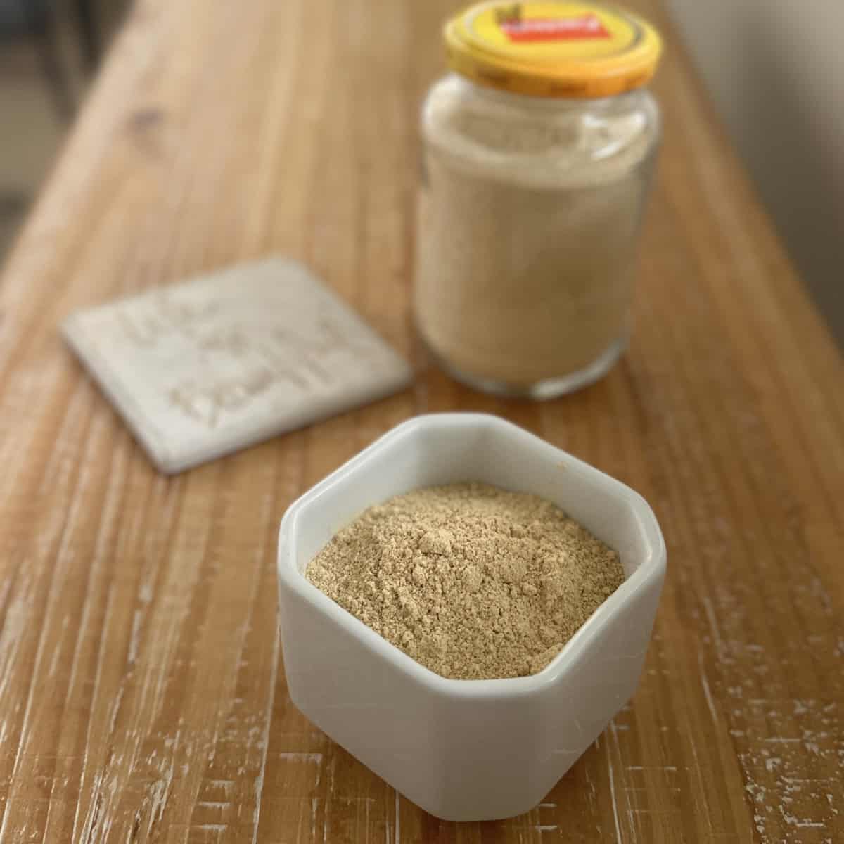 Chutney powder made with Chutney powder recipe in a white bowl and glass container on a wooden board with a tile on the side.