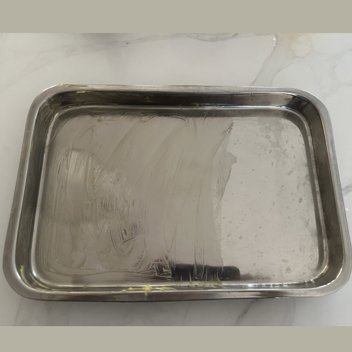 A metal tray greased with ghee on it.