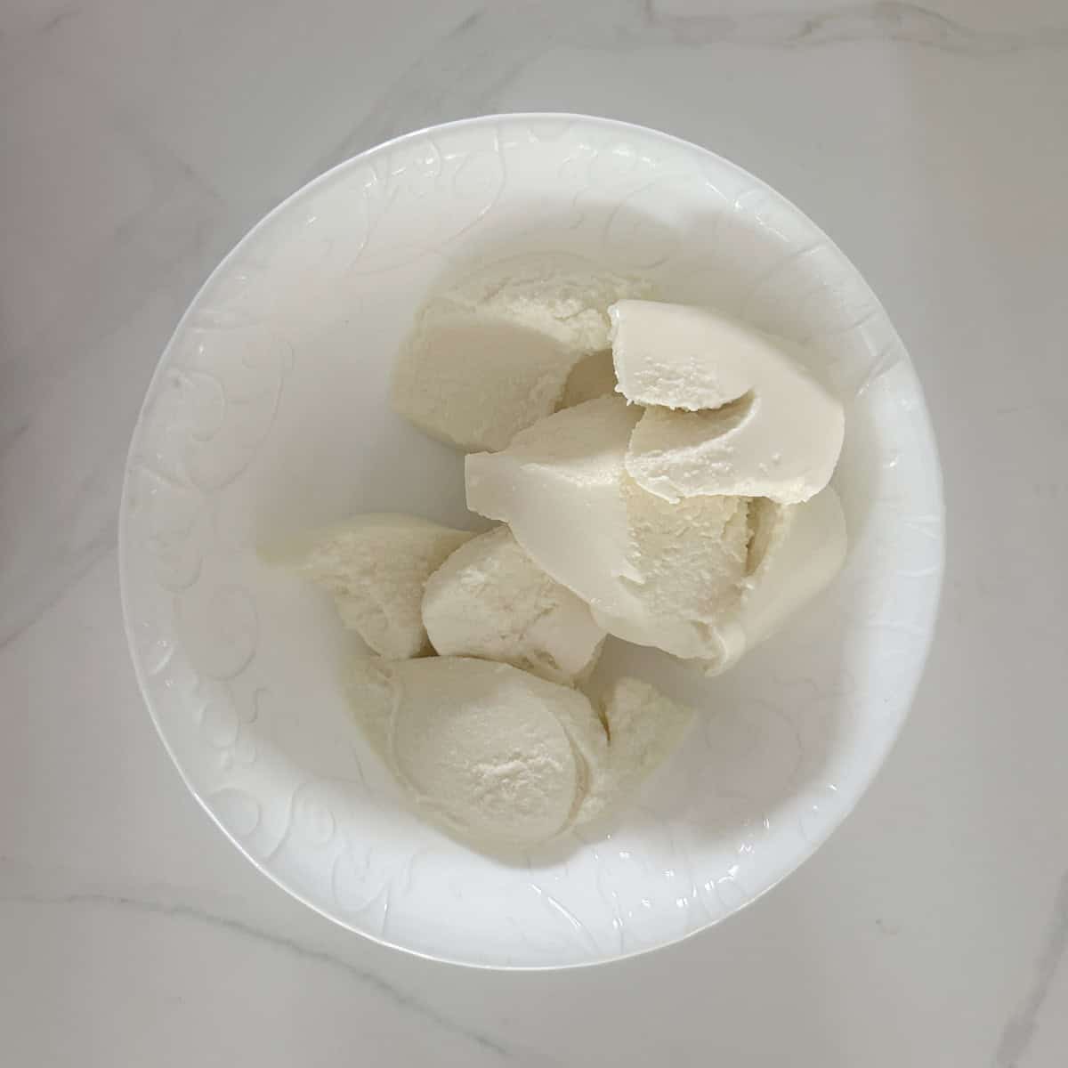 A white bowl filled with ricotta cheese.