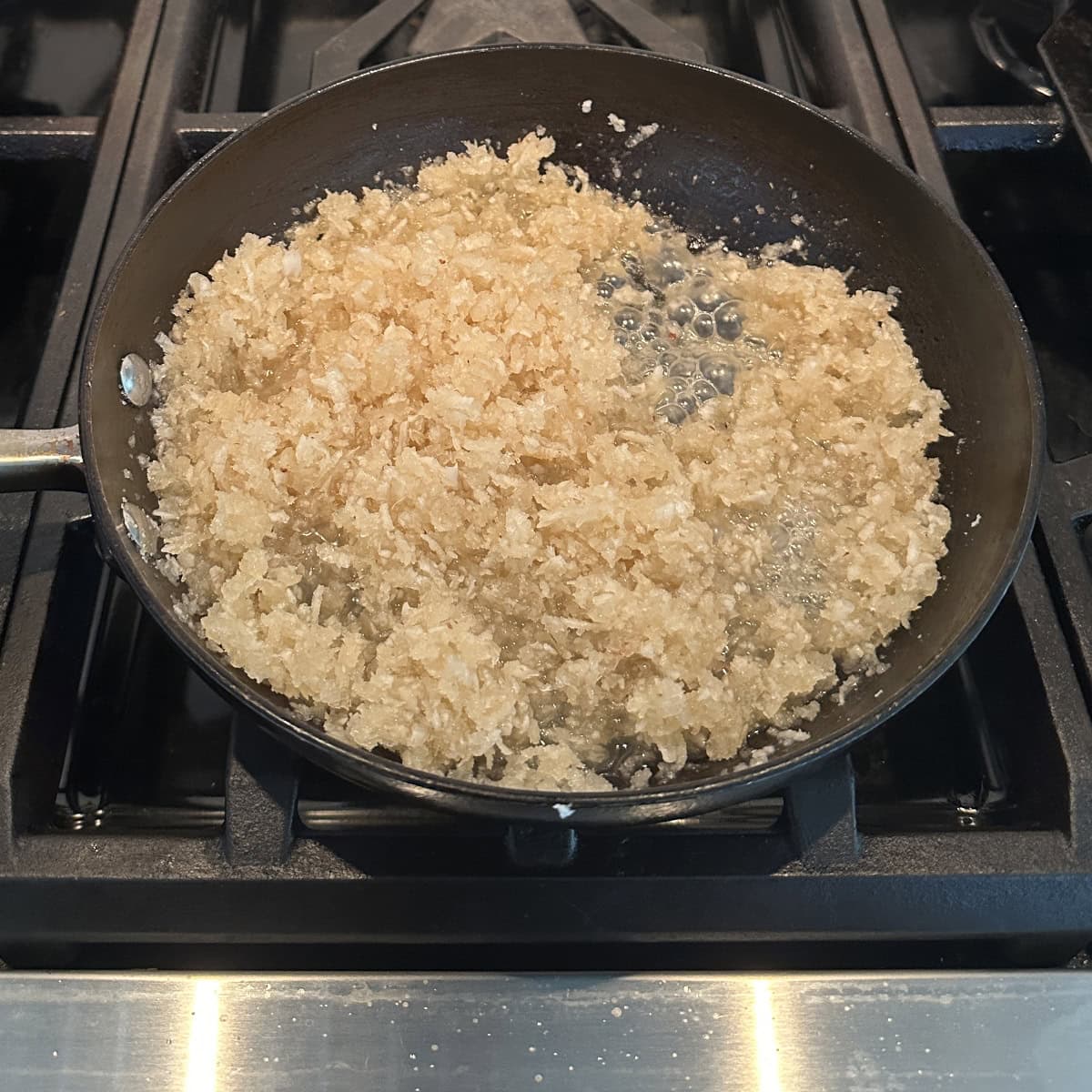 A pan with grated coconut and sugar in it.