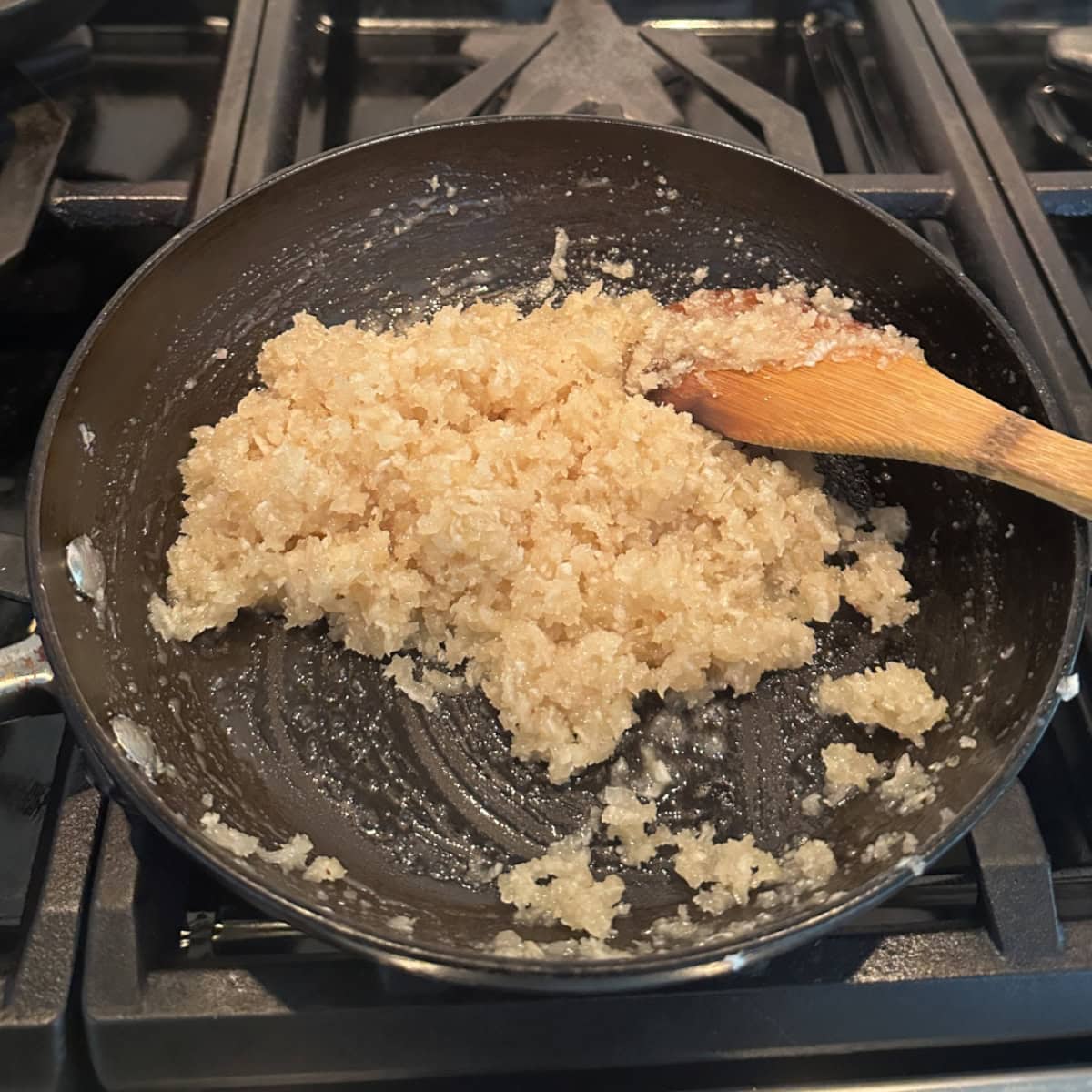 A pan with grate coconut and sugar cooking on the stove.