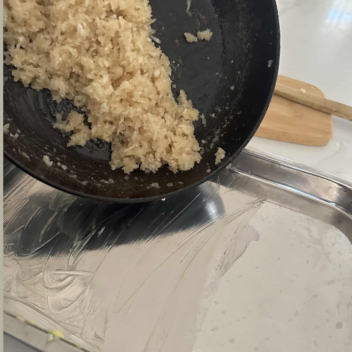 A pan with coconut burfi transferred to a tray sitting on top of a counter.