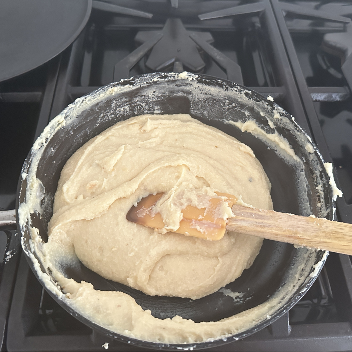 Ricotta cheese peda mixture with a spatula , leaving sides on pan and ready to be cooled and rolled.