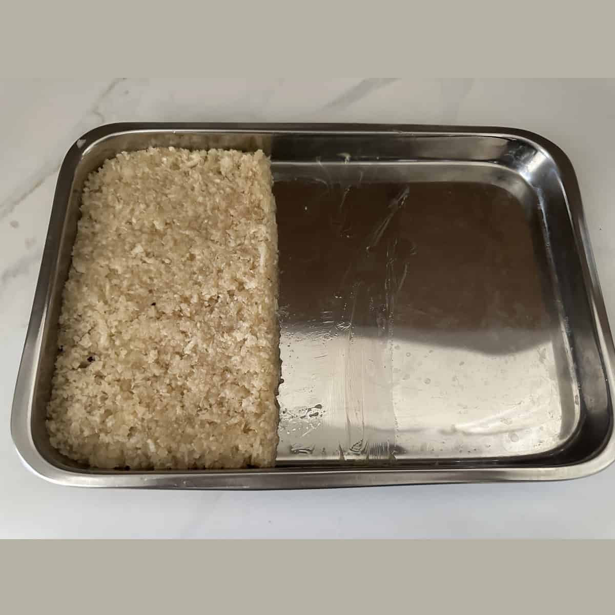 A metal tray with coconut burfi in it.