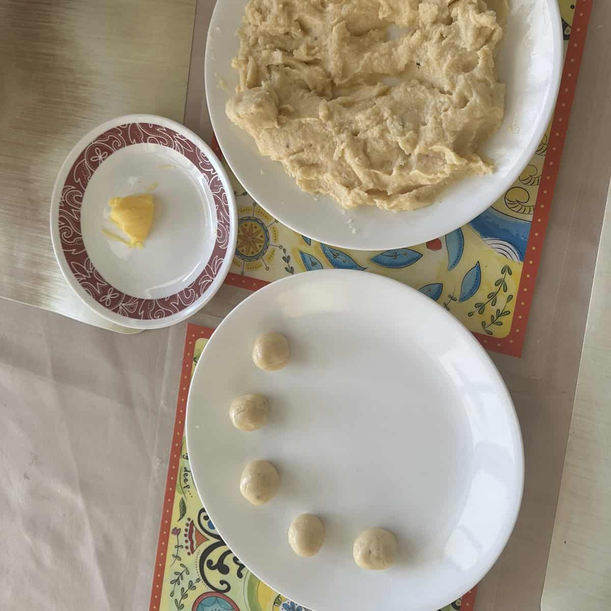 Ricotta cheese peda rolled and served on white plate and with ghee and the mixture in the background.