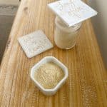 chutney powder made with chutney powder recipe in a white container and glass container on a wooden board and decorative tiles.
