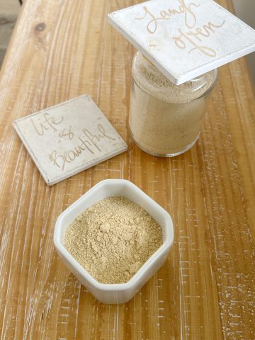 chutney powder made with chutney powder recipe in a white container and glass container on a wooden board and decorative tiles.