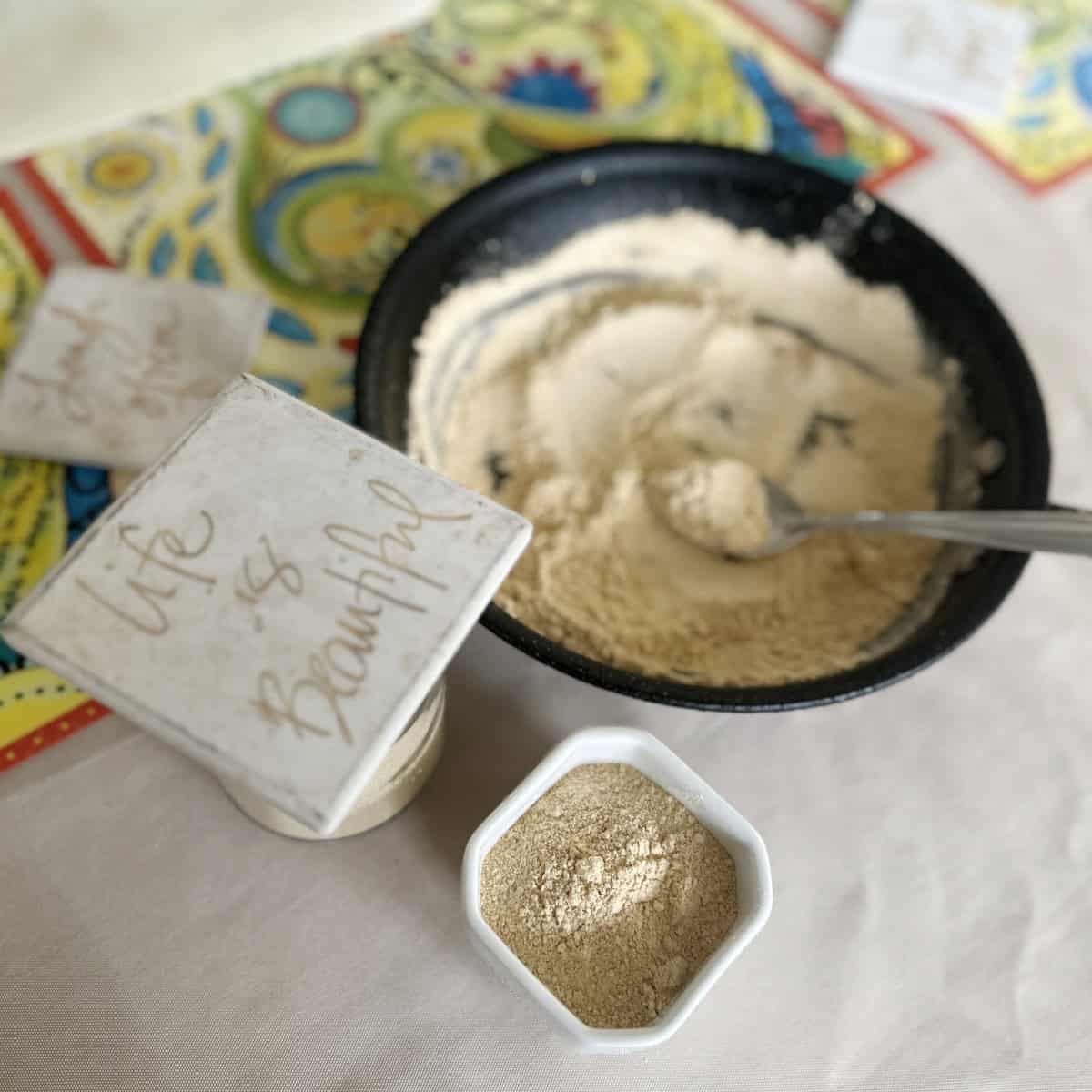chutney powder made with chutney powder recipe in a white container and black pan with decorative tiles.