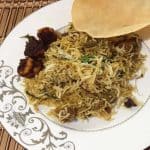 Mutton biryani served on a ceramic pate with pappad and fried shrimp made using mutton biryani easy recipe.