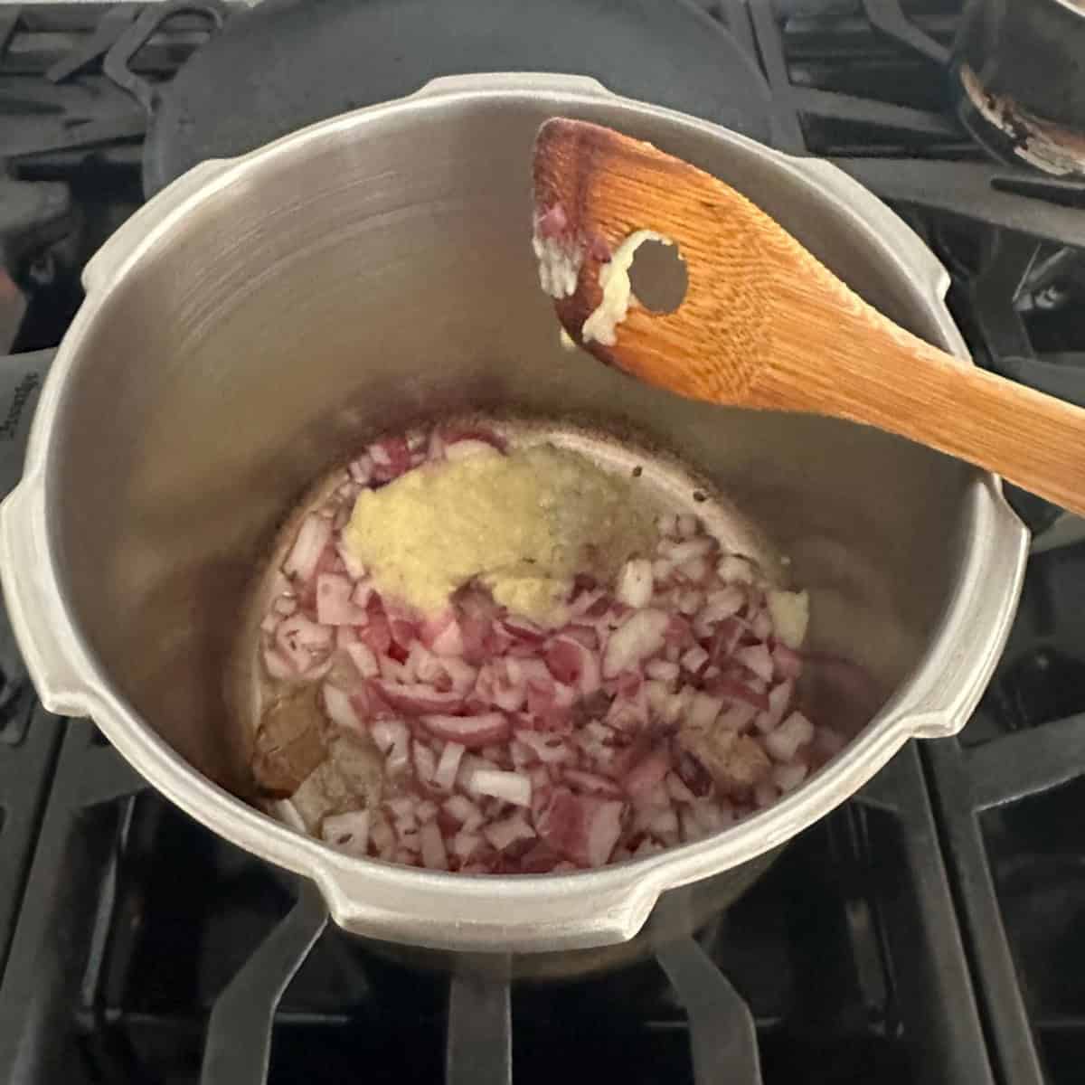 Dry Green Peas Curry base being cooked in a pressure cooker with onions and ginger garlic paste.