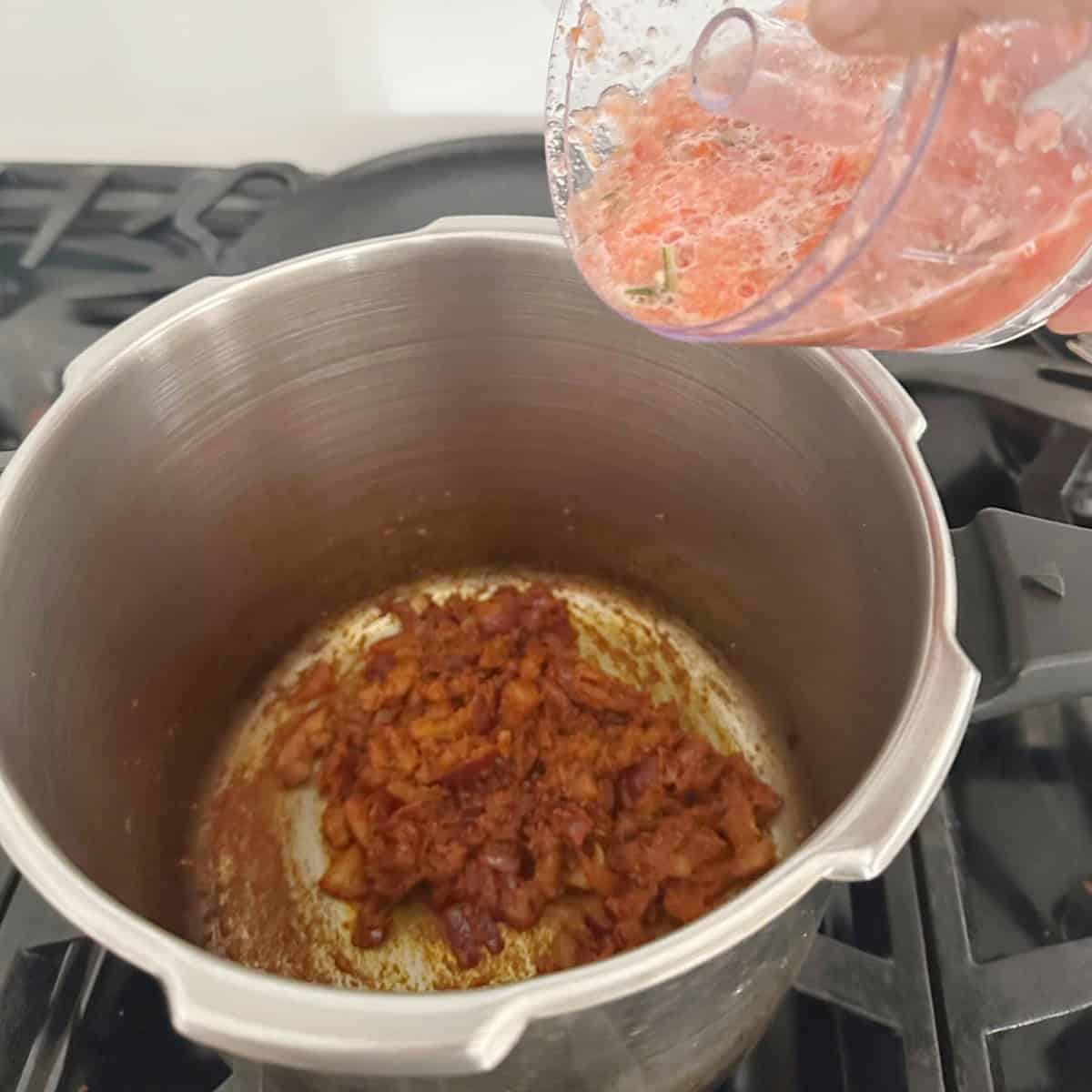 Dry Green Peas Curry base with tomatoes, onions and spices being cooked in a pressure cooker tomato paste being poured into it.