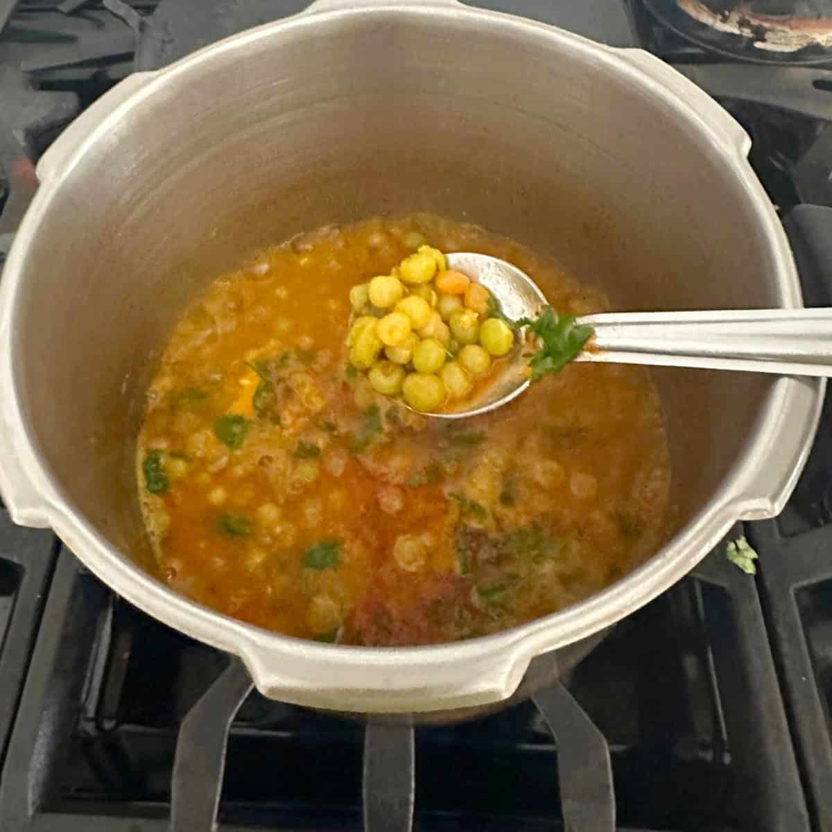 Dry Green Peas Curry cooked in a pressure cooker with a spoonful of curry.