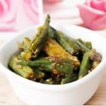 aloo bhindi in a white bowl with a pink tray in the background.