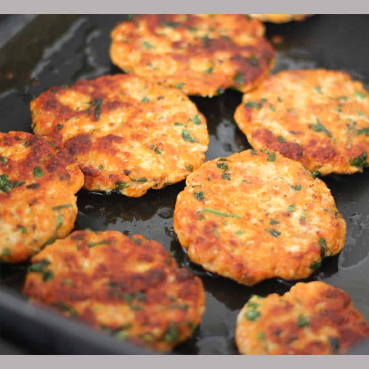 minced chicken patty cooking in a pan.