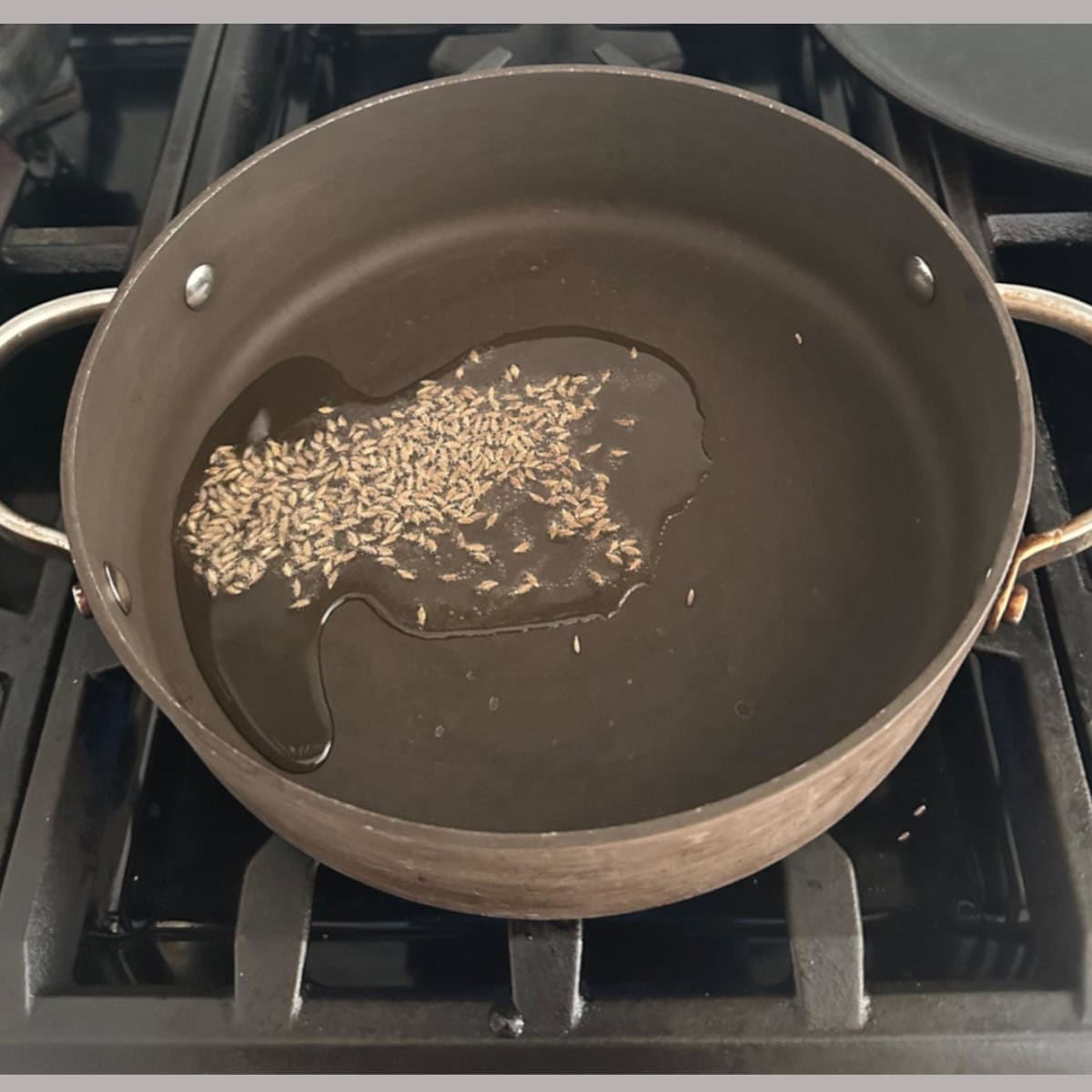cumin spluttering in oil in a pan.