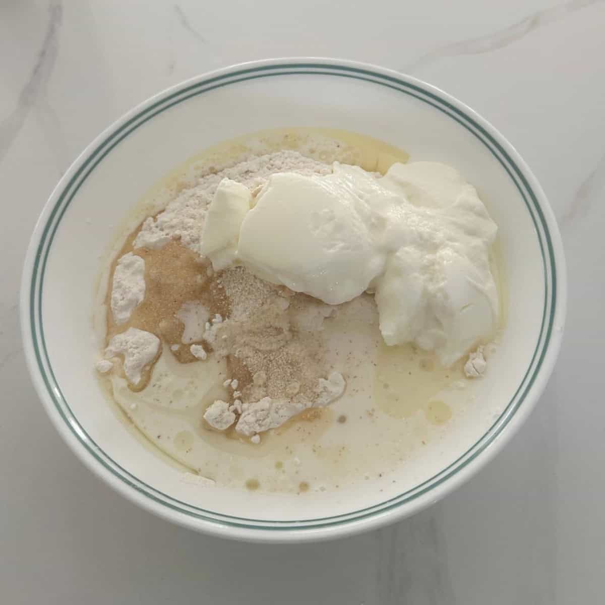 bhatura bread ingredients to be mixed to make dough in a white container.