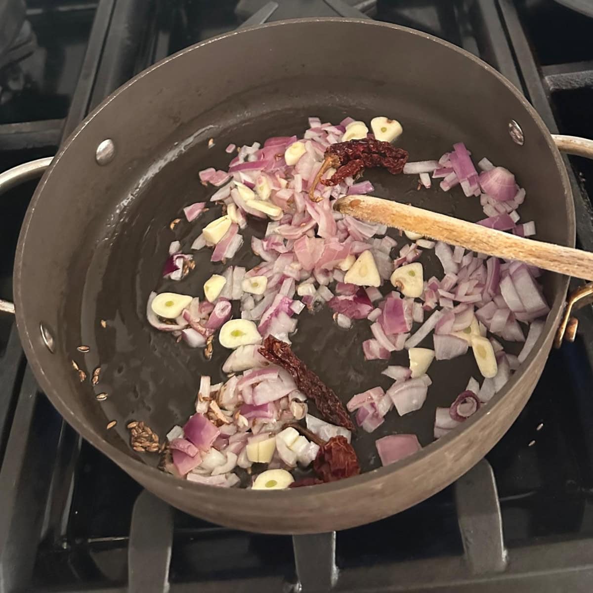 sautee onions, garlic, and red chili in a black pan.
