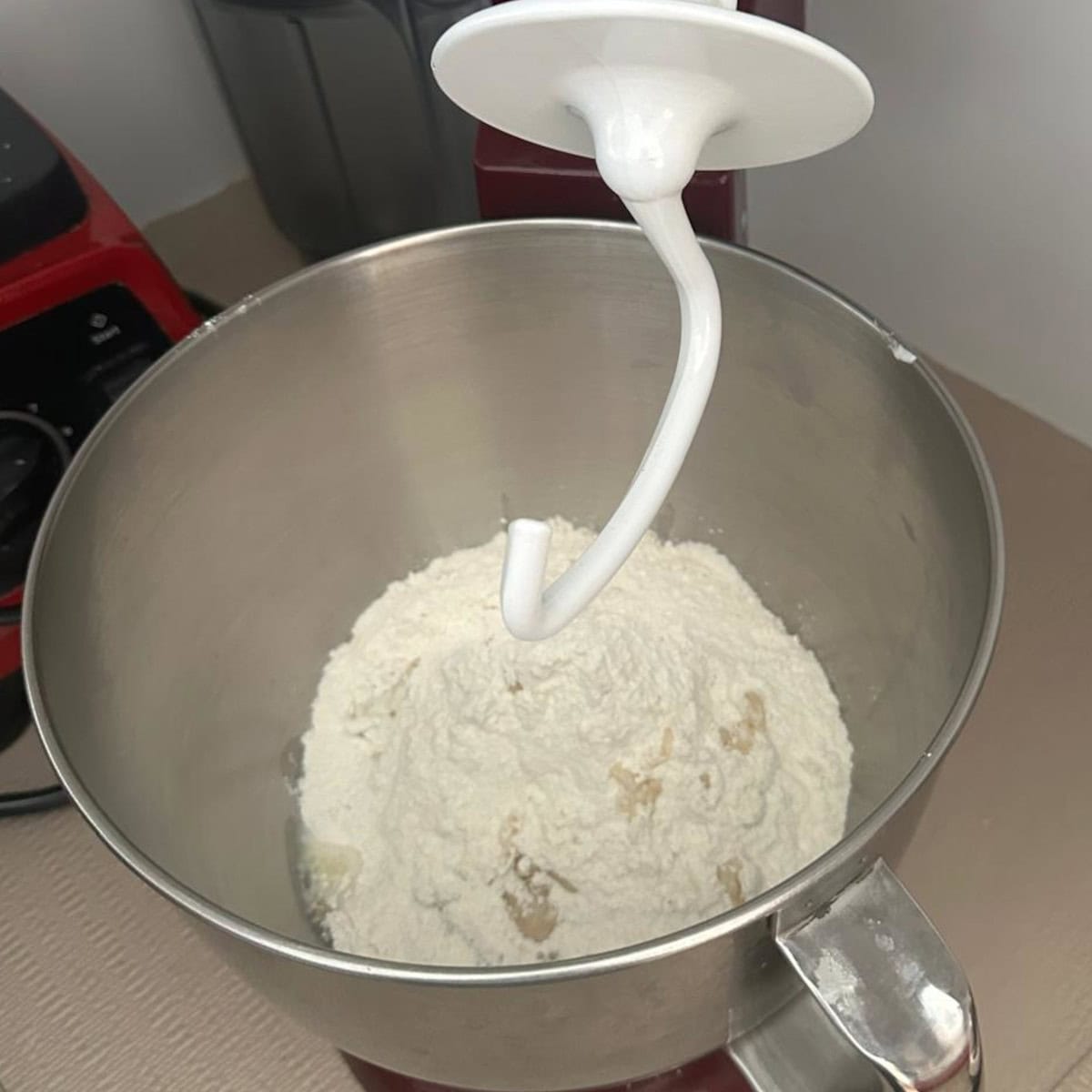 bhatura bread dough being kneaded in a stand mixer.