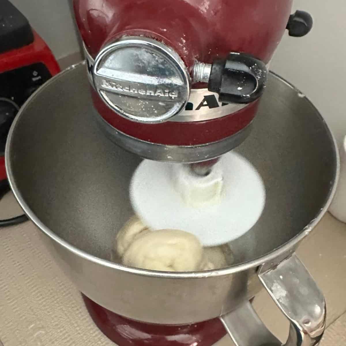 bhatura bread dough being kneaded in a stand mixer.