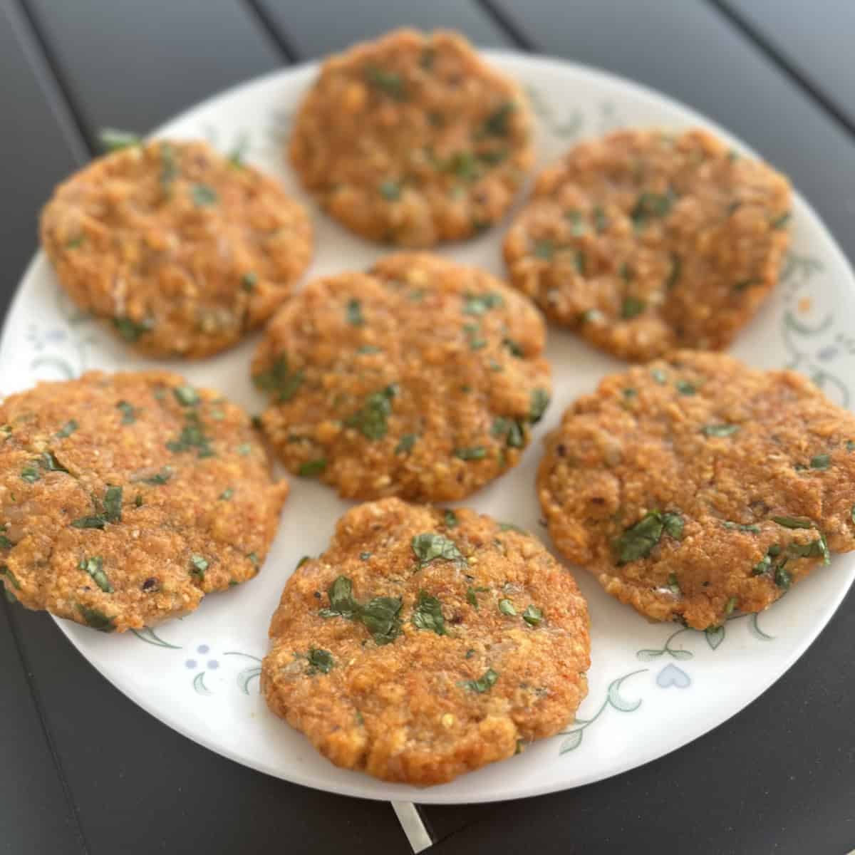Minced chicken patty shaped and on a white plate ready to be cooked.