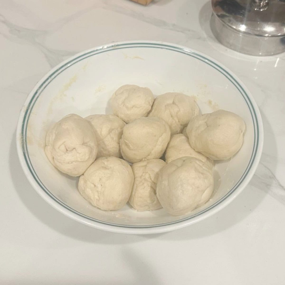bhatura bread dough divided to be rolled in a white container.