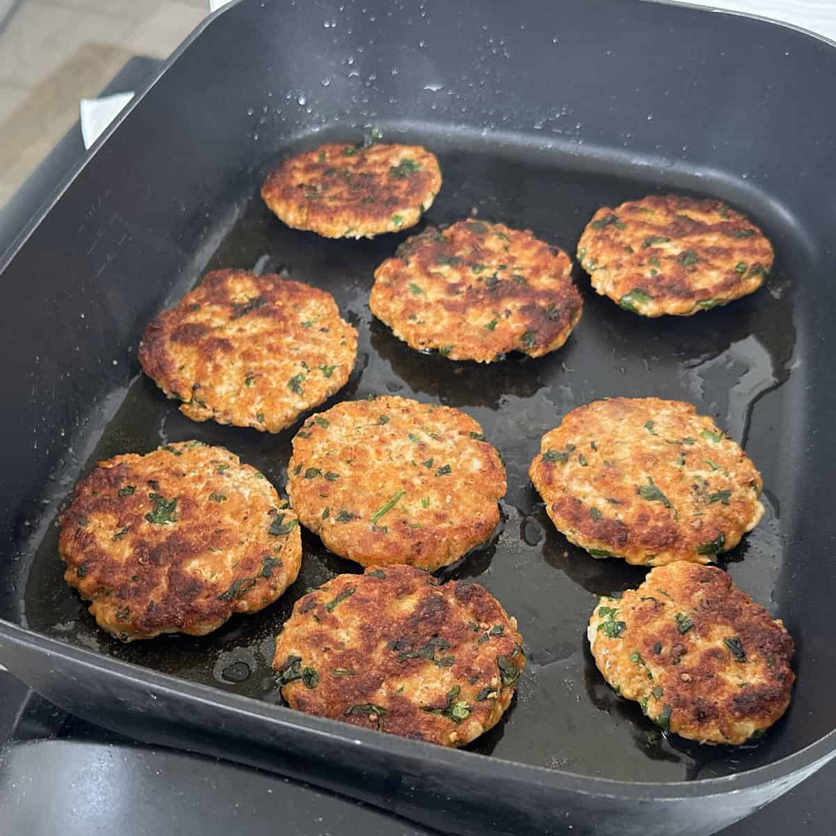 Minced chicken cooked in a black electric pan.