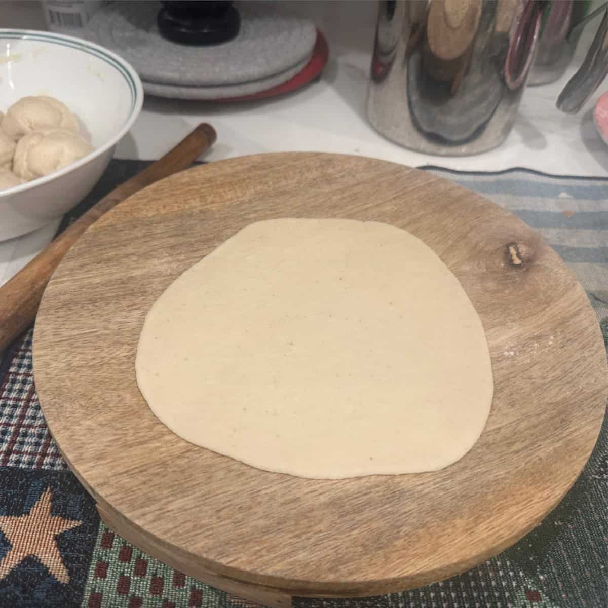 bhatura bread rolled out using a rolling pin on a rolling board.