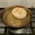 Bhatura Bread fried in oil in a steel wok.
