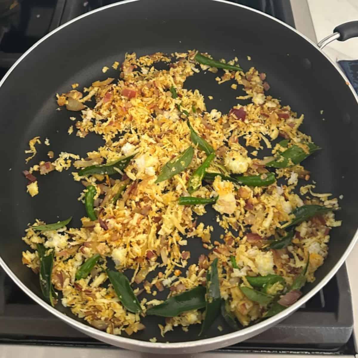 cabbage stir fry preparation in a black pan on stove top.