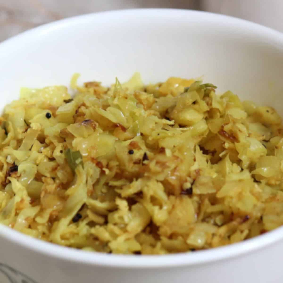 Cabbage coconut stir fry in a white bowl.