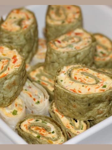 Veggie Cream cheese Roll ups served stacked in a white bowl.