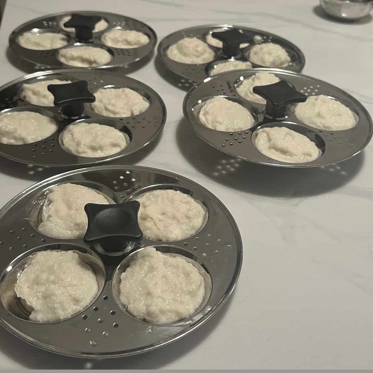 idli batter poured into idli steamer moulds.