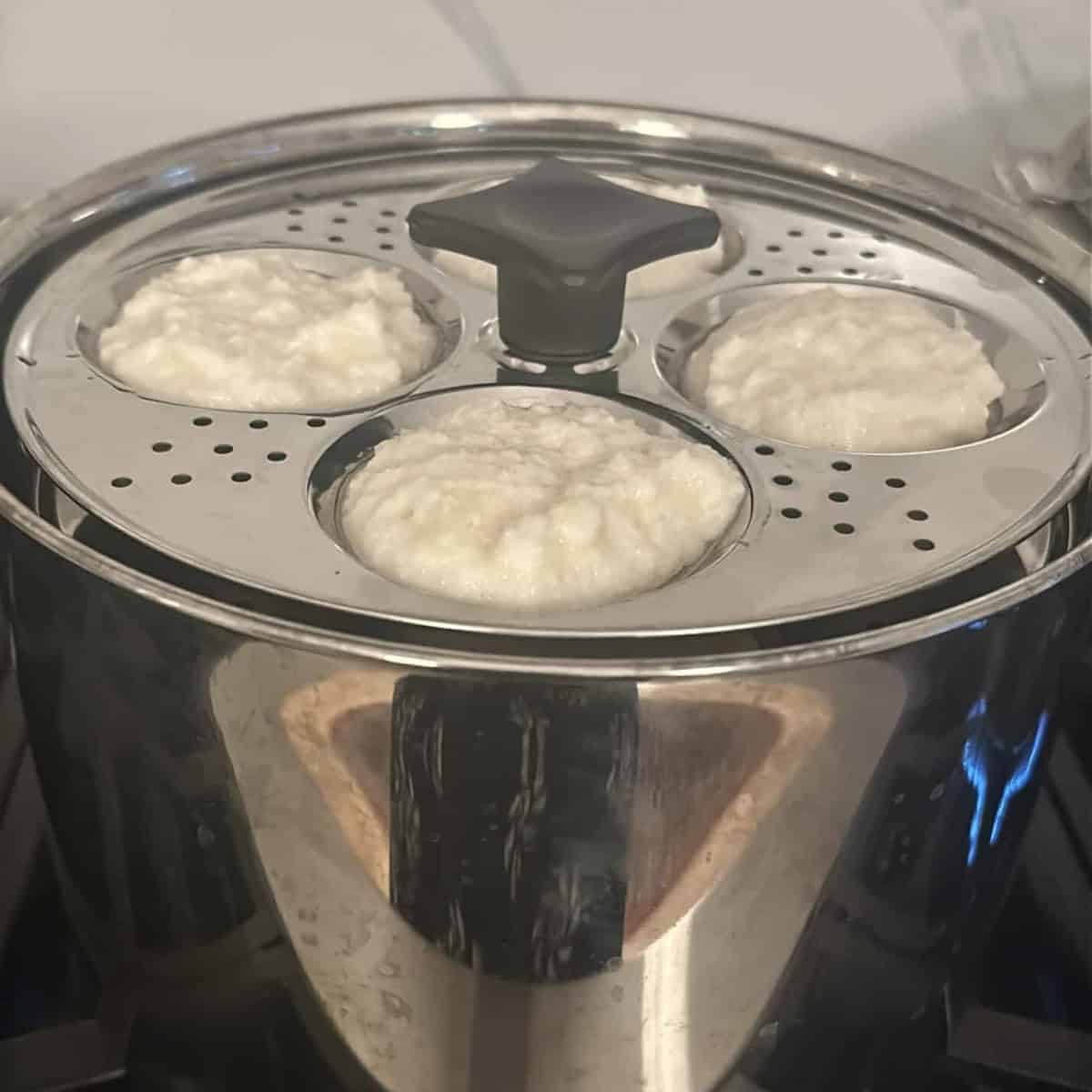 idli batter ready to be steamed in a steel idli cooker.