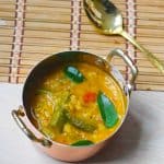 Sambar or lentil soup made with kerala sambar recipe served in a copper vessel with a golden spoon next to it.