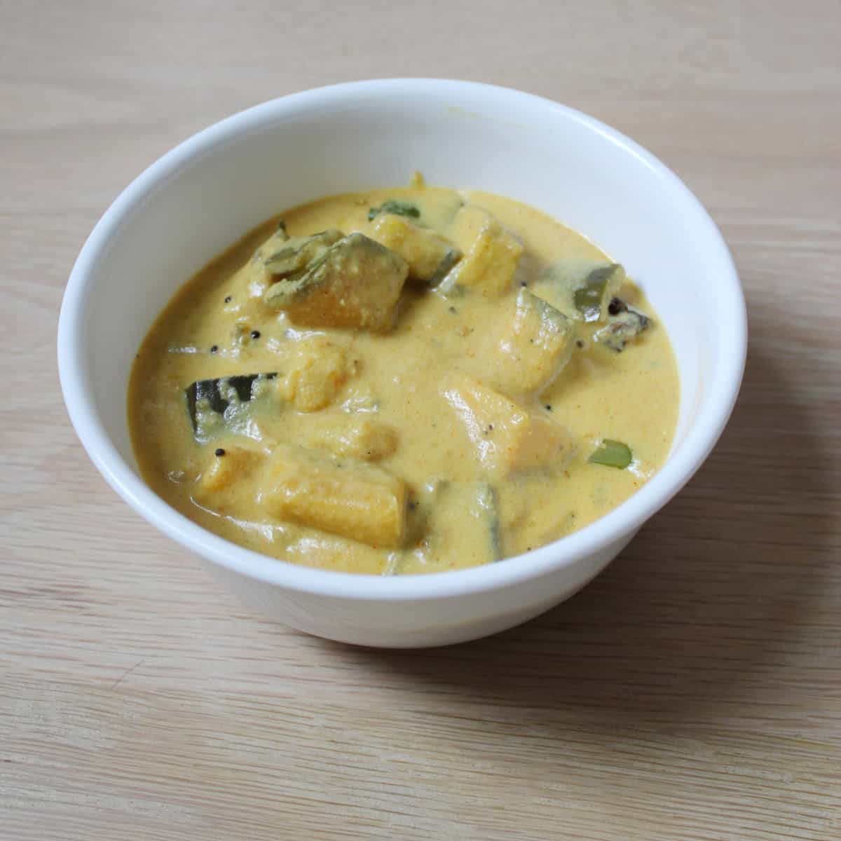 Kaalan served in a white bowl on a wooden board.
