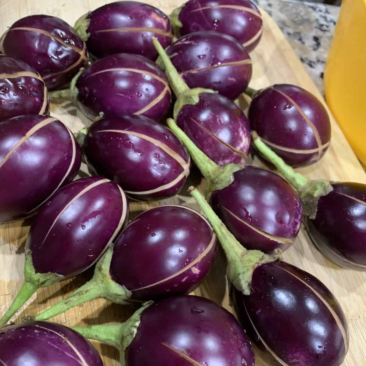 Bright purple eggplants with green stems, fresh and ripe for culinary use.